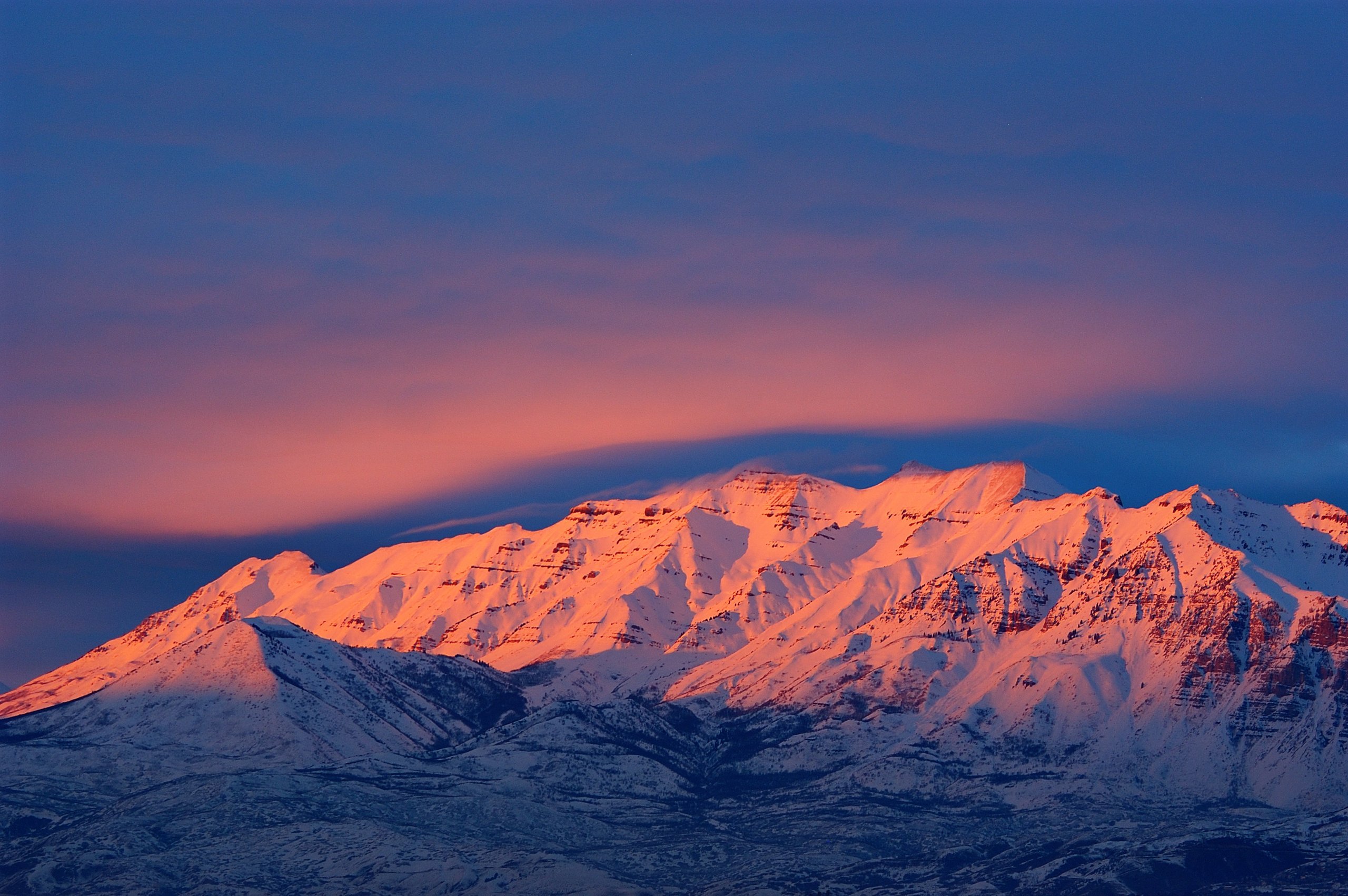 Mount Timpanogos at sunset, its long snow-capped ridgeline catching alpenglow above Utah Valley — the reclining profile behind the 'sleeping princess' legend.