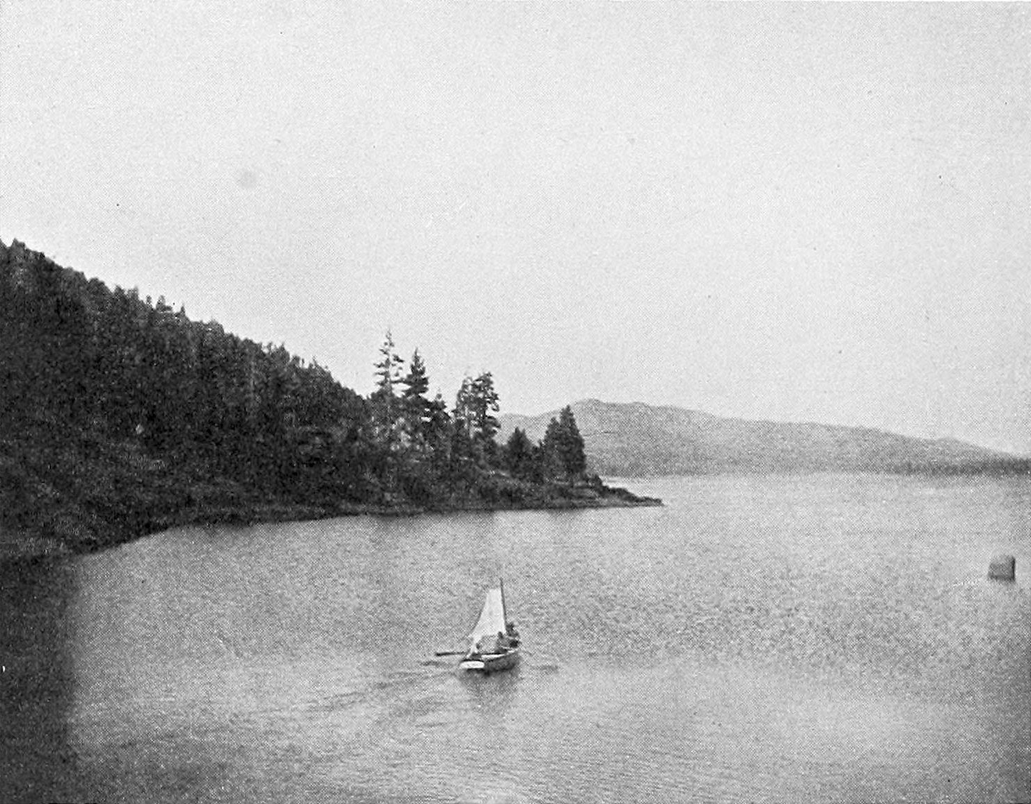 A small sailboat on Bear Lake around 1906, the reservoir held behind Frank Brown's dam, pine slopes falling to the water.