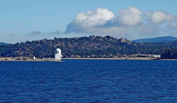 The white dome of the Big Bear Solar Observatory standing on its causeway out in the lake, the north shore behind it.