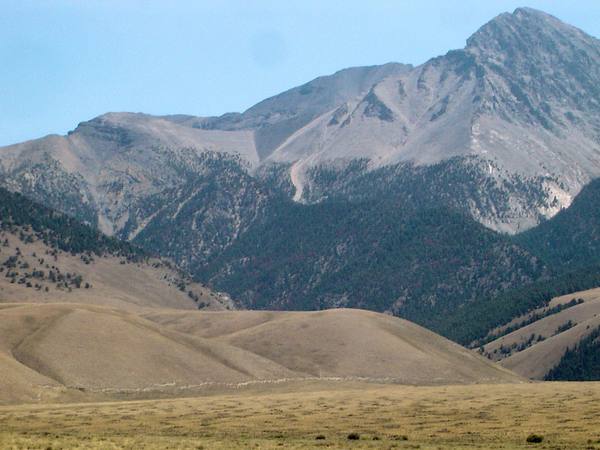 Borah Peak rising above tan foothills, the 1983 fault scarp a faint line along the base of the hills