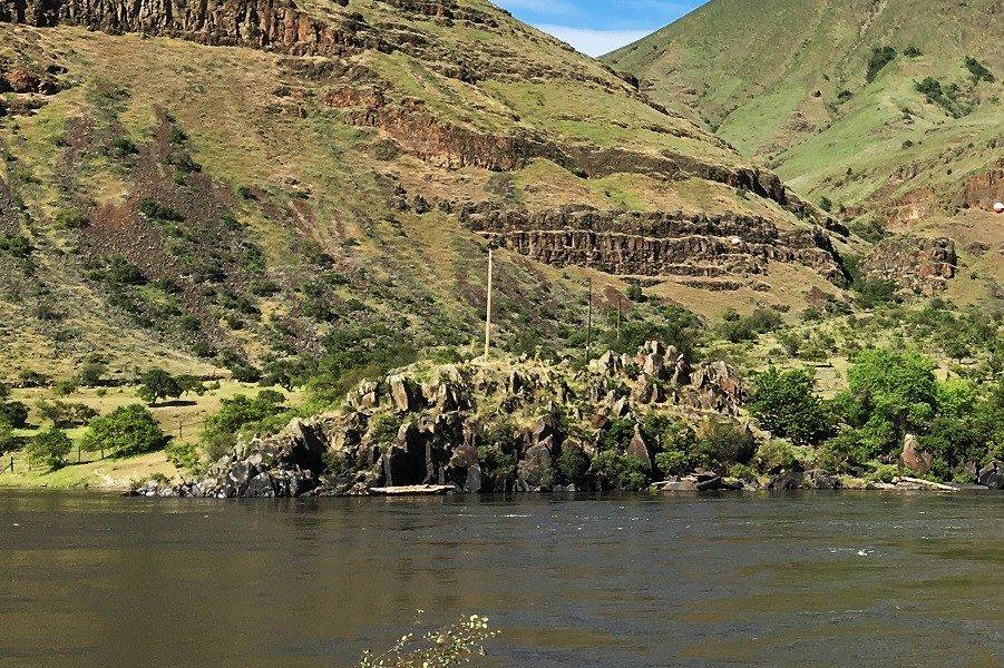 The Snake River at Buffalo Eddy, dark basalt outcrops along the far bank below grassy, rim-rocked canyon walls
