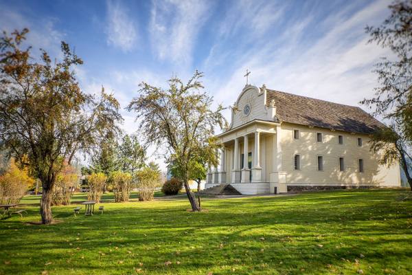 The white-columned Mission of the Sacred Heart on its lawn among autumn trees at Cataldo