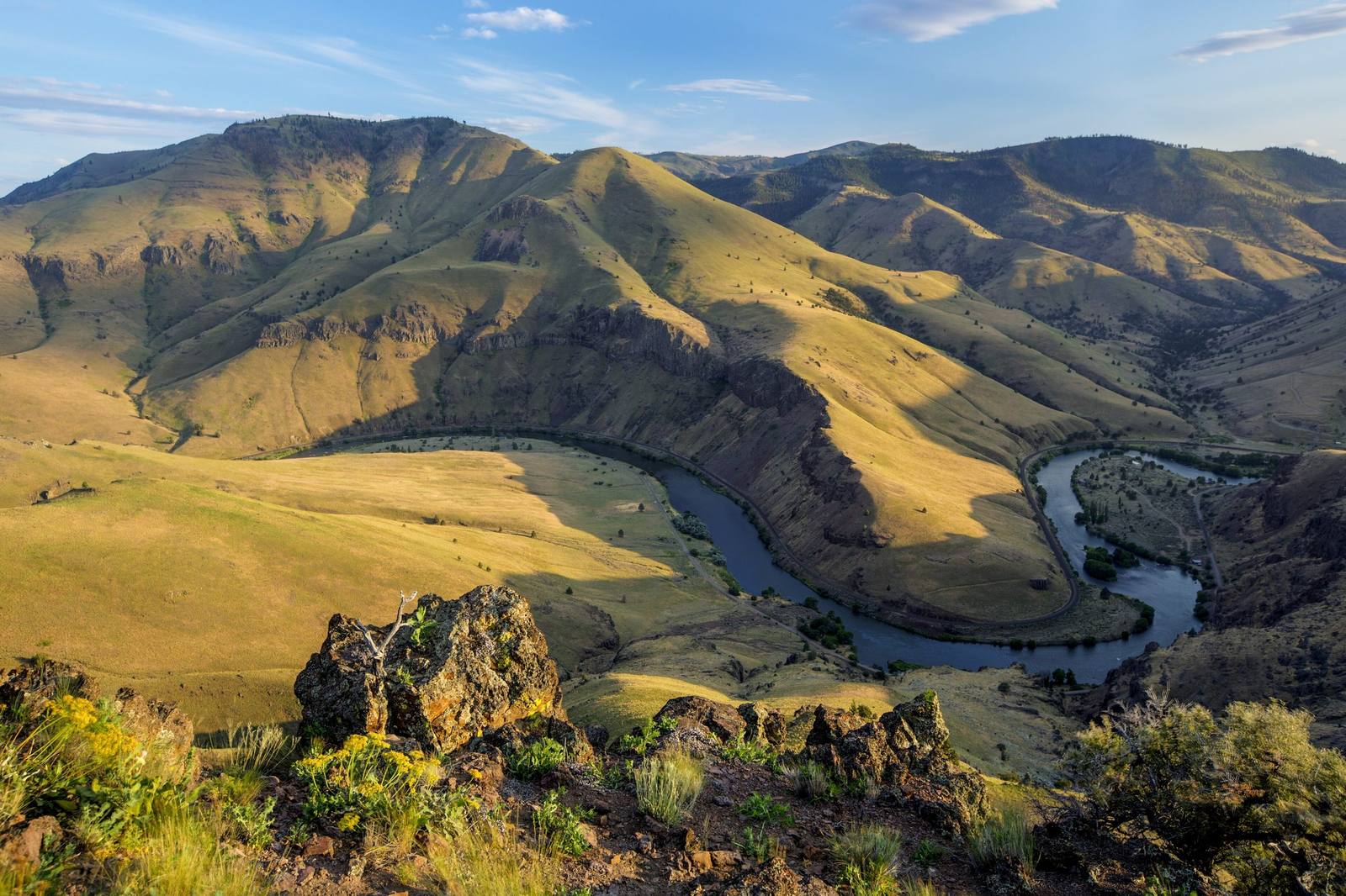 The Deschutes River bending through its canyon below grassy basalt ridges in evening light