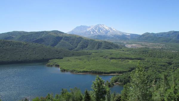 Coldwater Lake below green ridges, Mount St. Helens rising beyond the valley the 1980 avalanche filled