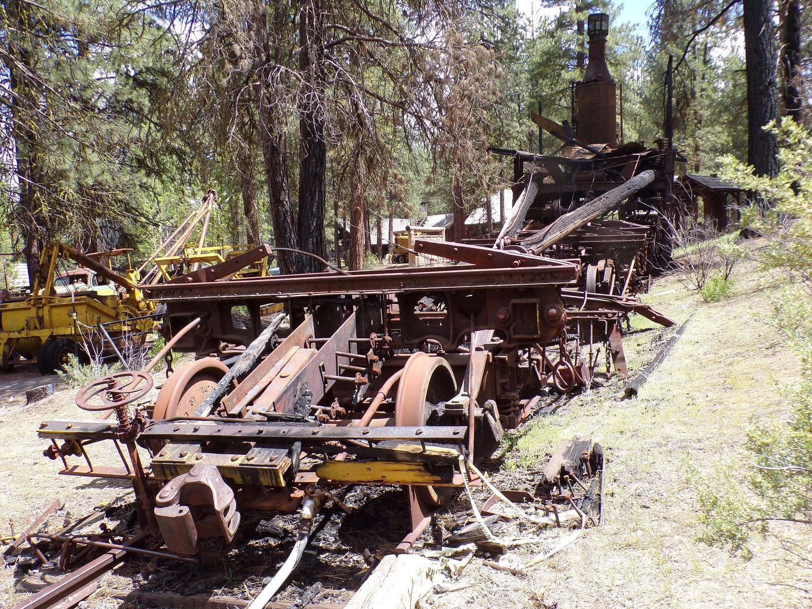 A rusted McGiffert log loader among other old logging machines under the ponderosa pines at Collier Memorial State Park