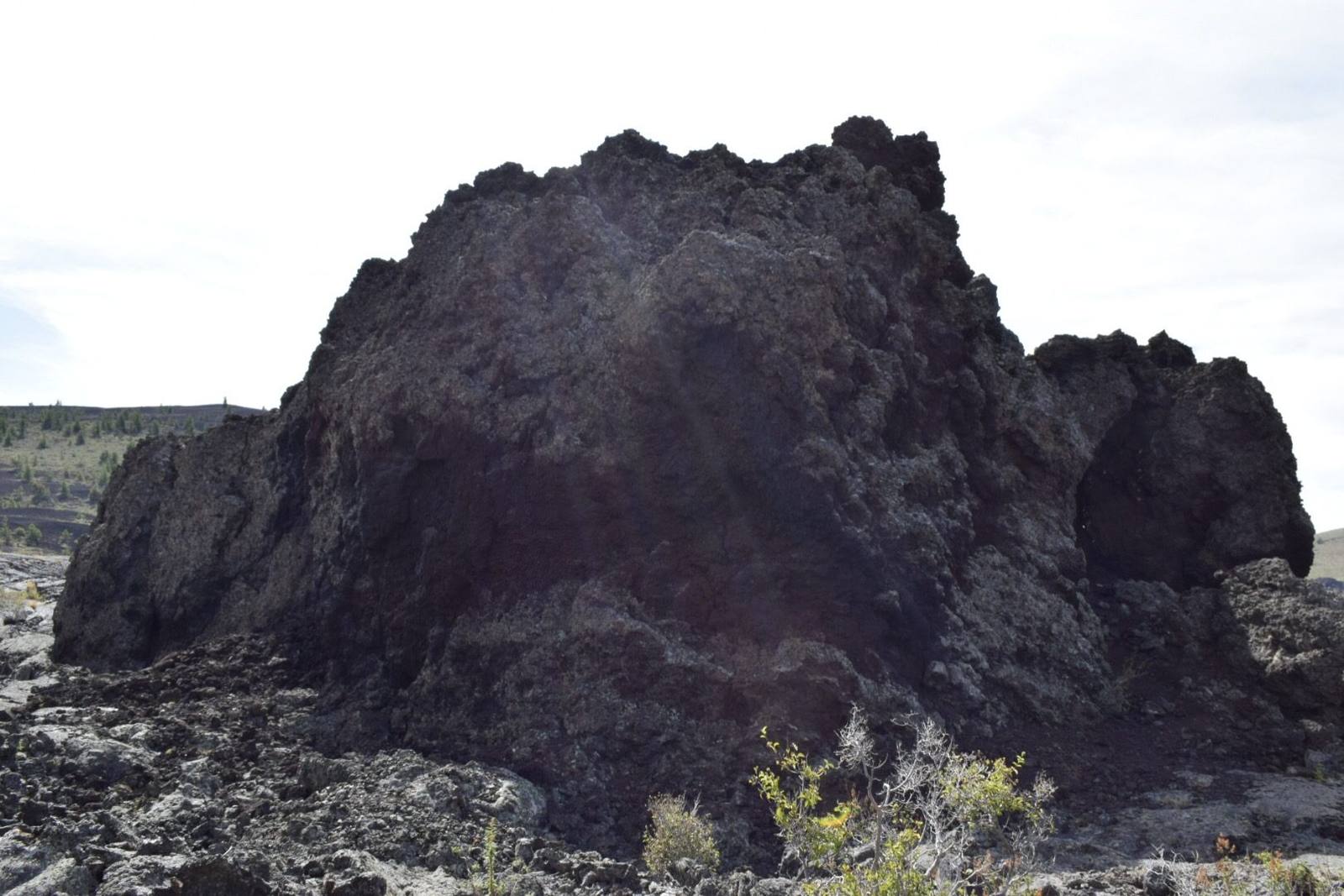 A jagged mass of black lava rising from the broken surface of a flow at Craters of the Moon