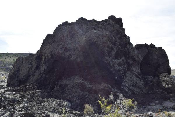 A jagged mass of black lava rising from the broken surface of a flow at Craters of the Moon