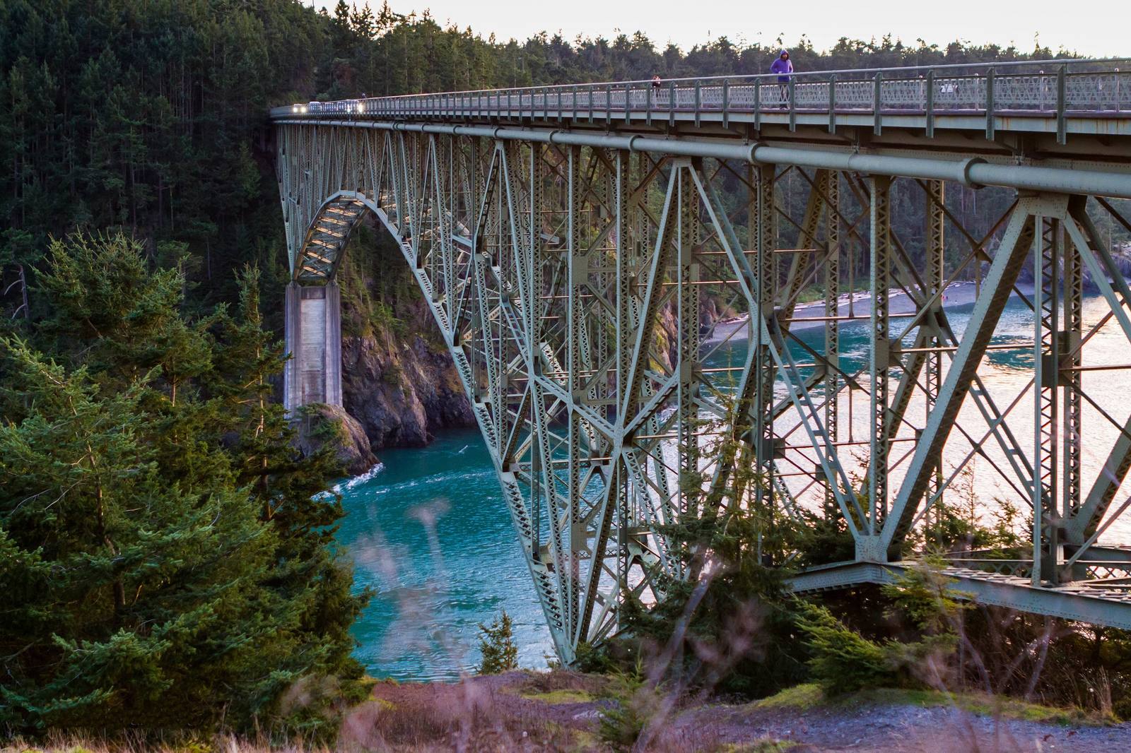 The steel arch of the Deception Pass Bridge spanning the narrow green channel between Whidbey and Fidalgo islands, forest on both sides