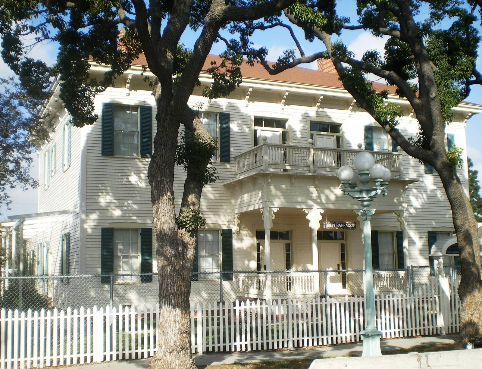 The surviving officers' quarters of Drum Barracks in Wilmington, a white two-storey building with green shutters behind a picket fence.