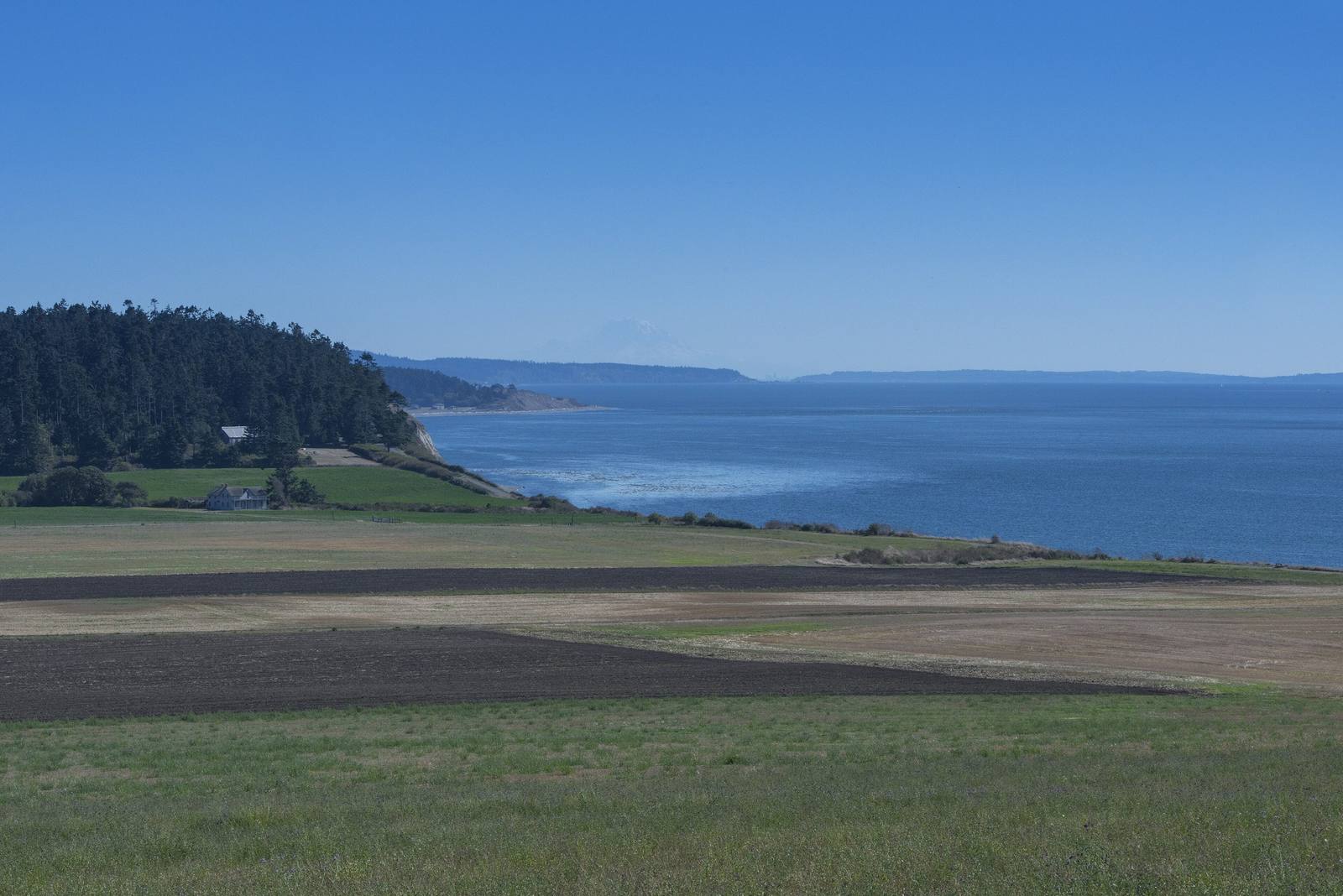 The open farm fields of Ebey's Prairie running to the bluff above the Strait of Juan de Fuca, the far shore fading into haze