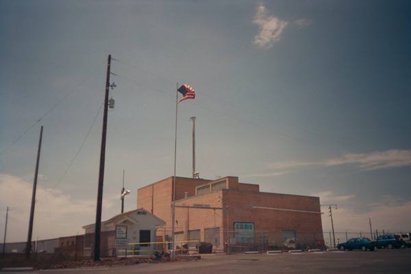The brick reactor building of Experimental Breeder Reactor I beneath a flagpole in the desert