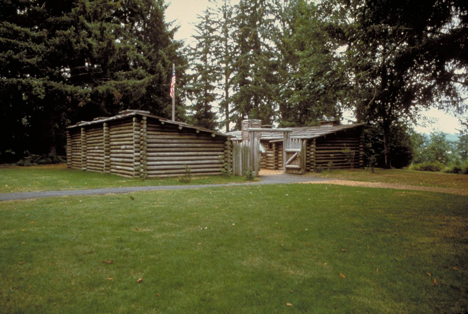 The 1955 replica of Fort Clatsop, two log rows and a gate in a clearing among spruce