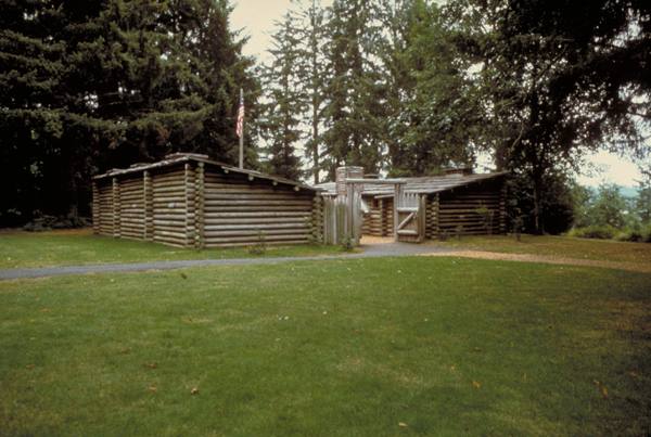 The 1955 replica of Fort Clatsop, two log rows and a gate in a clearing among spruce