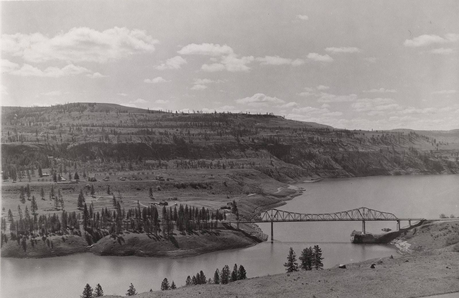 The Fort Spokane site around 1943, seen from north of the Spokane River, a steel truss bridge crossing the river below terraced bluffs