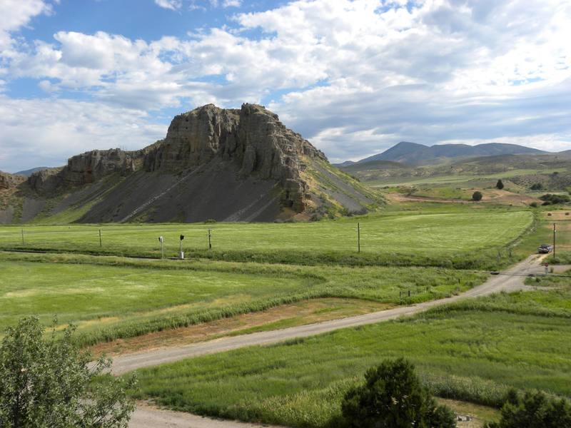 The red limestone cliff at Red Rock Pass above green fields and a gravel road