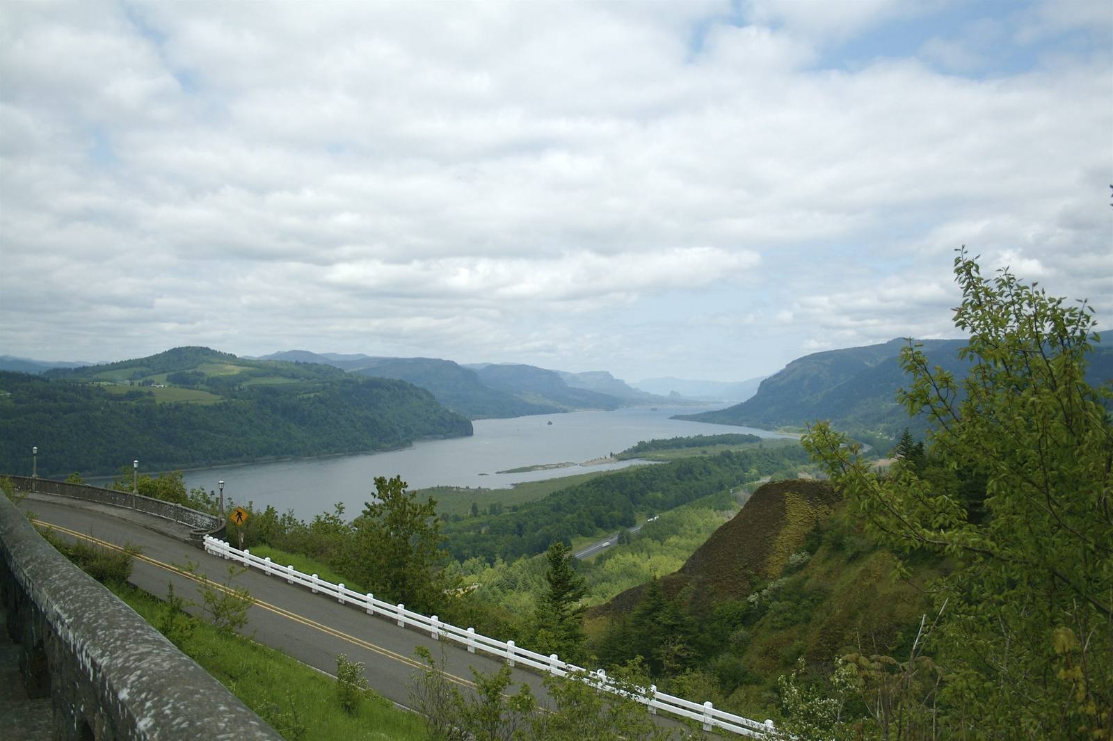 The Historic Columbia River Highway curving along the gorge wall, its stone guard wall in the foreground and the Columbia below