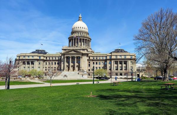 The domed sandstone Idaho State Capitol across its lawn in spring