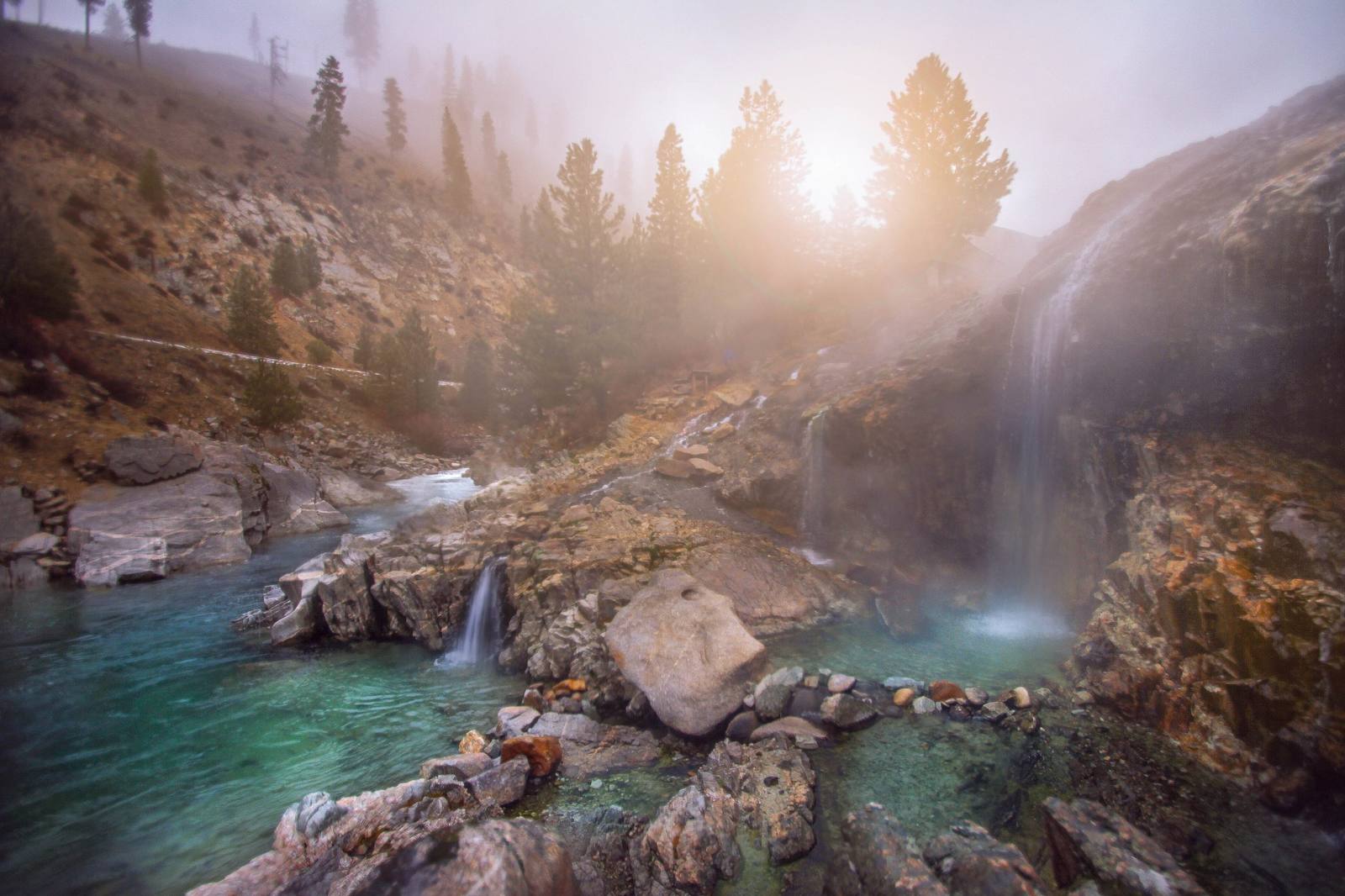Hot water falling from a rock ledge into steaming pools beside the South Fork of the Payette at Kirkham