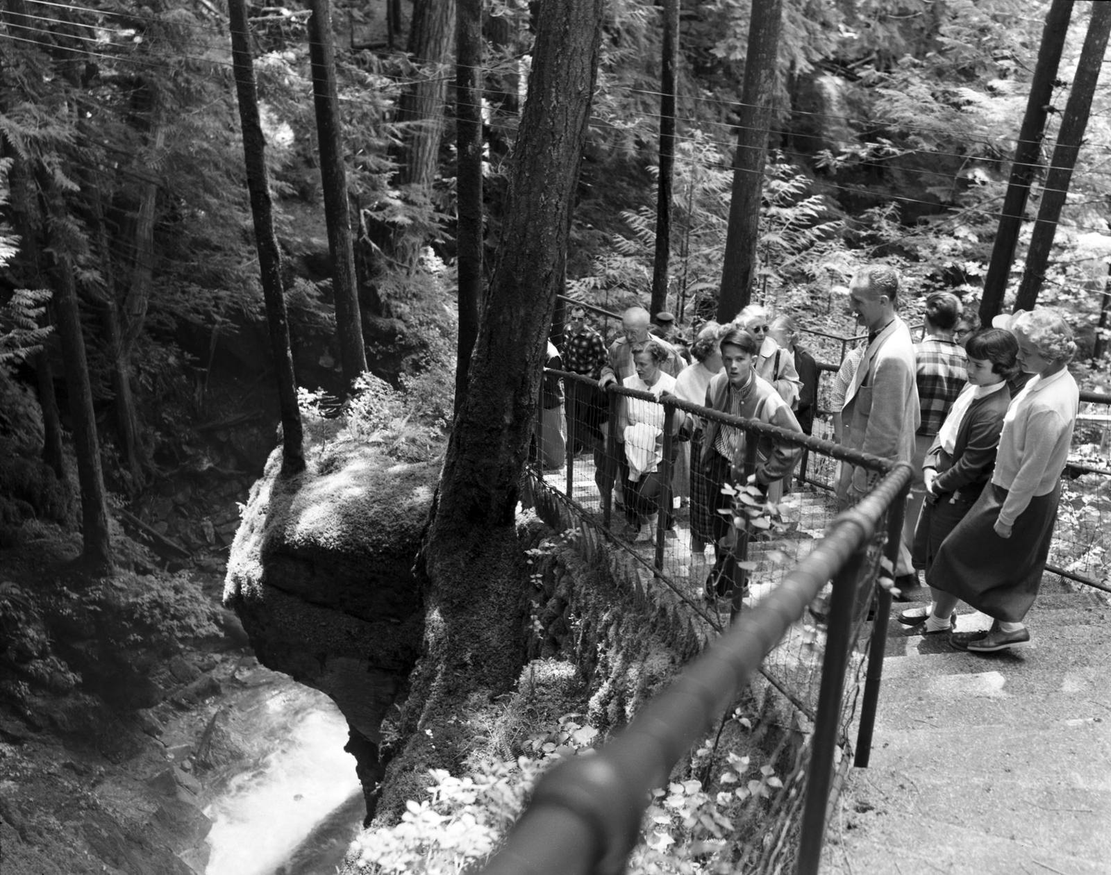 Tourists on a City Light tour around 1958 lining the railed trail above Ladder Creek's rock gorge behind the Gorge Powerhouse