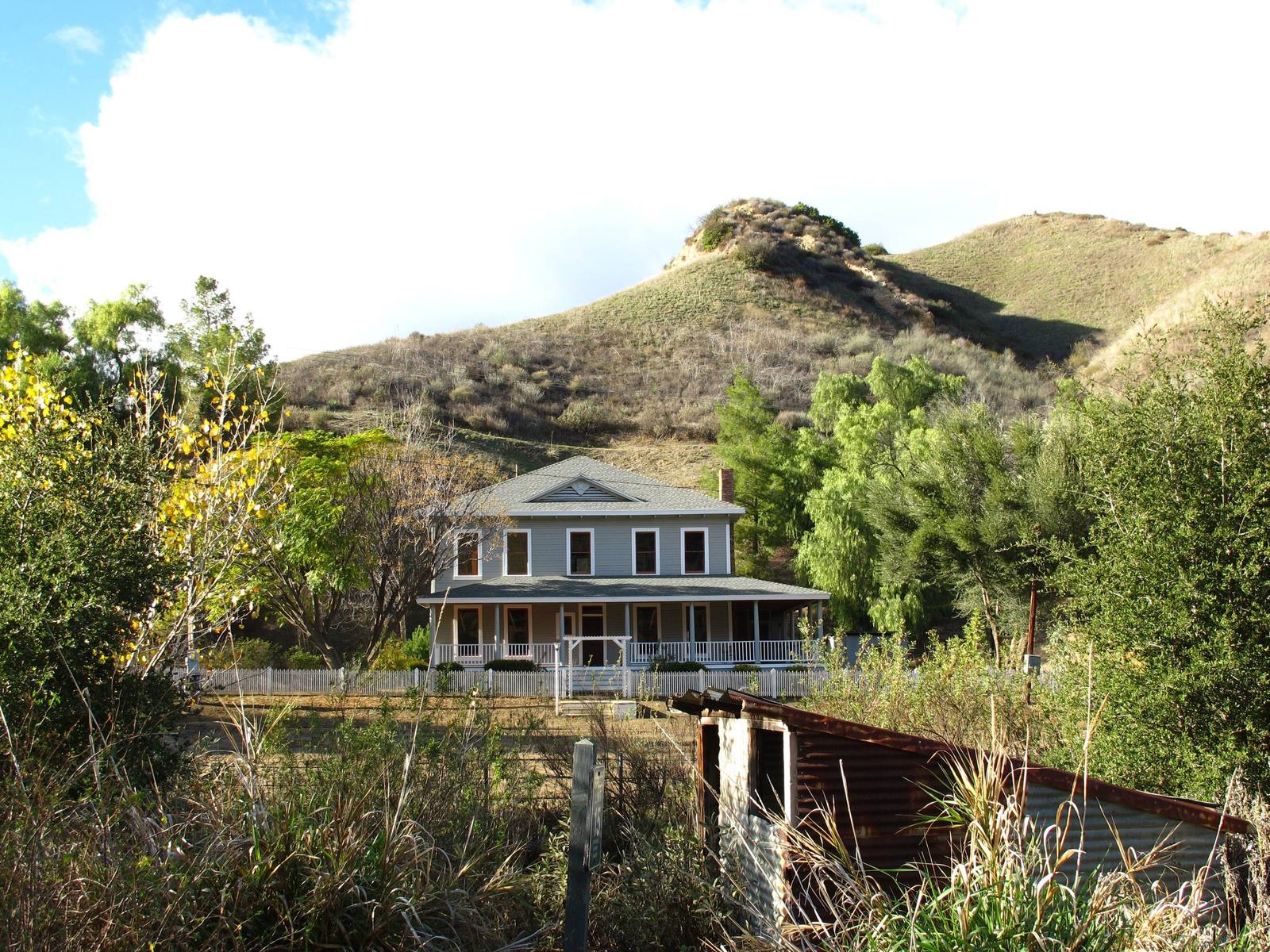 The C. A. Mentry house at Mentryville, a two-story wooden house below the bare hills of Pico Canyon.
