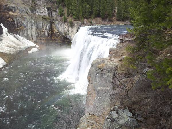 Upper Mesa Falls pouring over its rock ledge into the Henrys Fork, with spring snow on the canyon wall