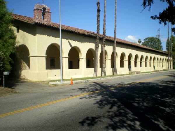 The convento at Mission San Fernando Rey de España, a long two-story adobe fronted by a colonnade of arches.