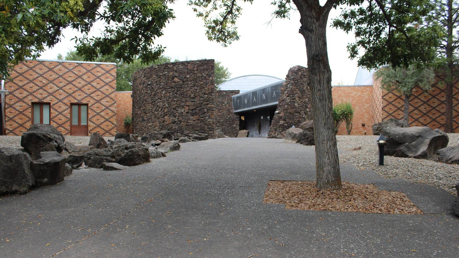 The courtyard of the Museum at Warm Springs, patterned brick walls and basalt stone set around a shade tree