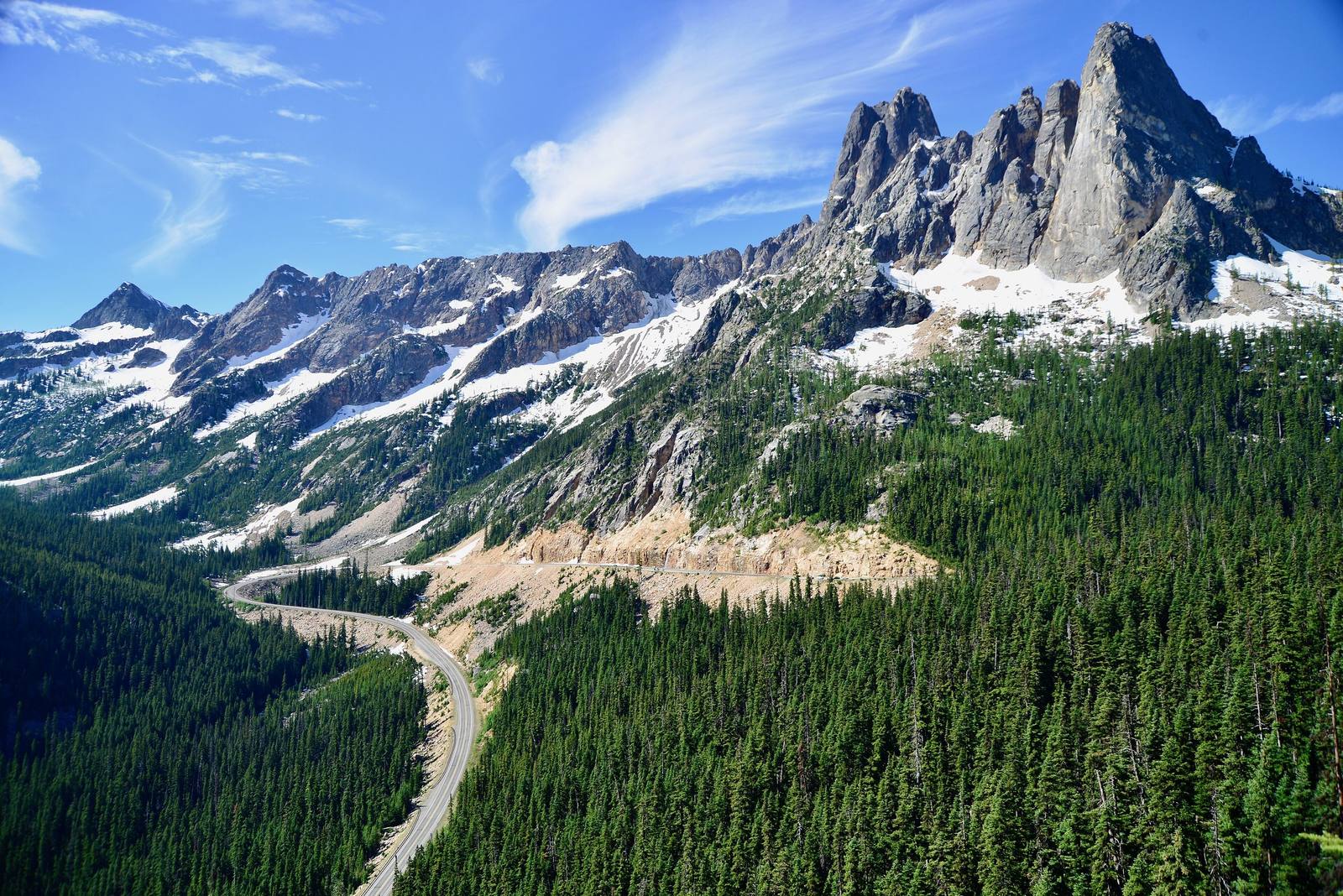 State Route 20 winding through forest below the granite spires of Liberty Bell Mountain at Washington Pass