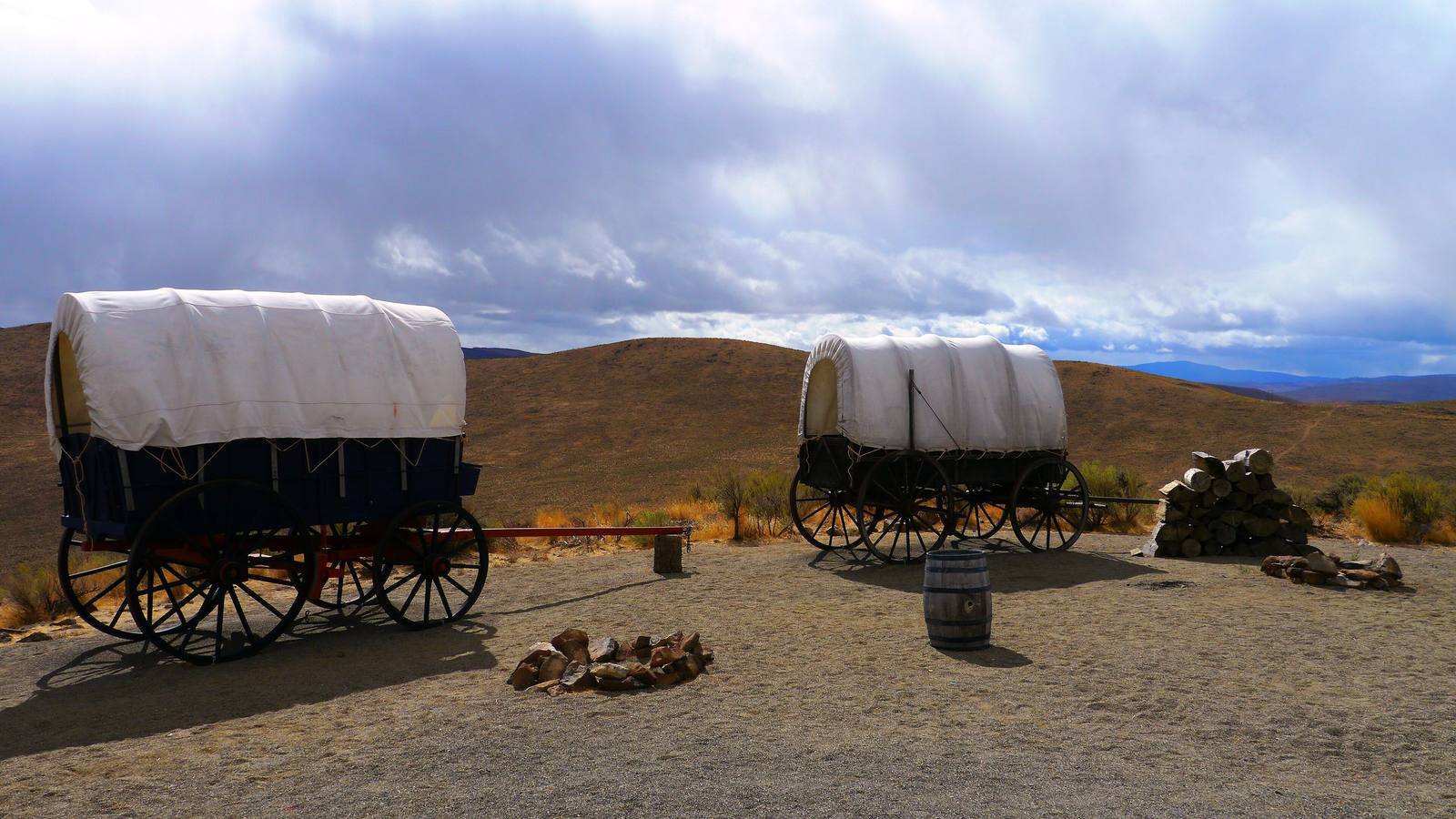 Covered wagons set out on Flagstaff Hill at the Oregon Trail Interpretive Center, dry sagebrush hills beyond