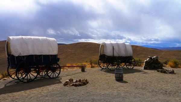 Covered wagons set out on Flagstaff Hill at the Oregon Trail Interpretive Center, dry sagebrush hills beyond