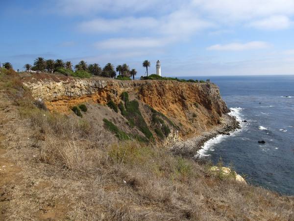 The Point Vicente headland dropping to the Pacific, the lighthouse small on the bluff above deep water close to shore.
