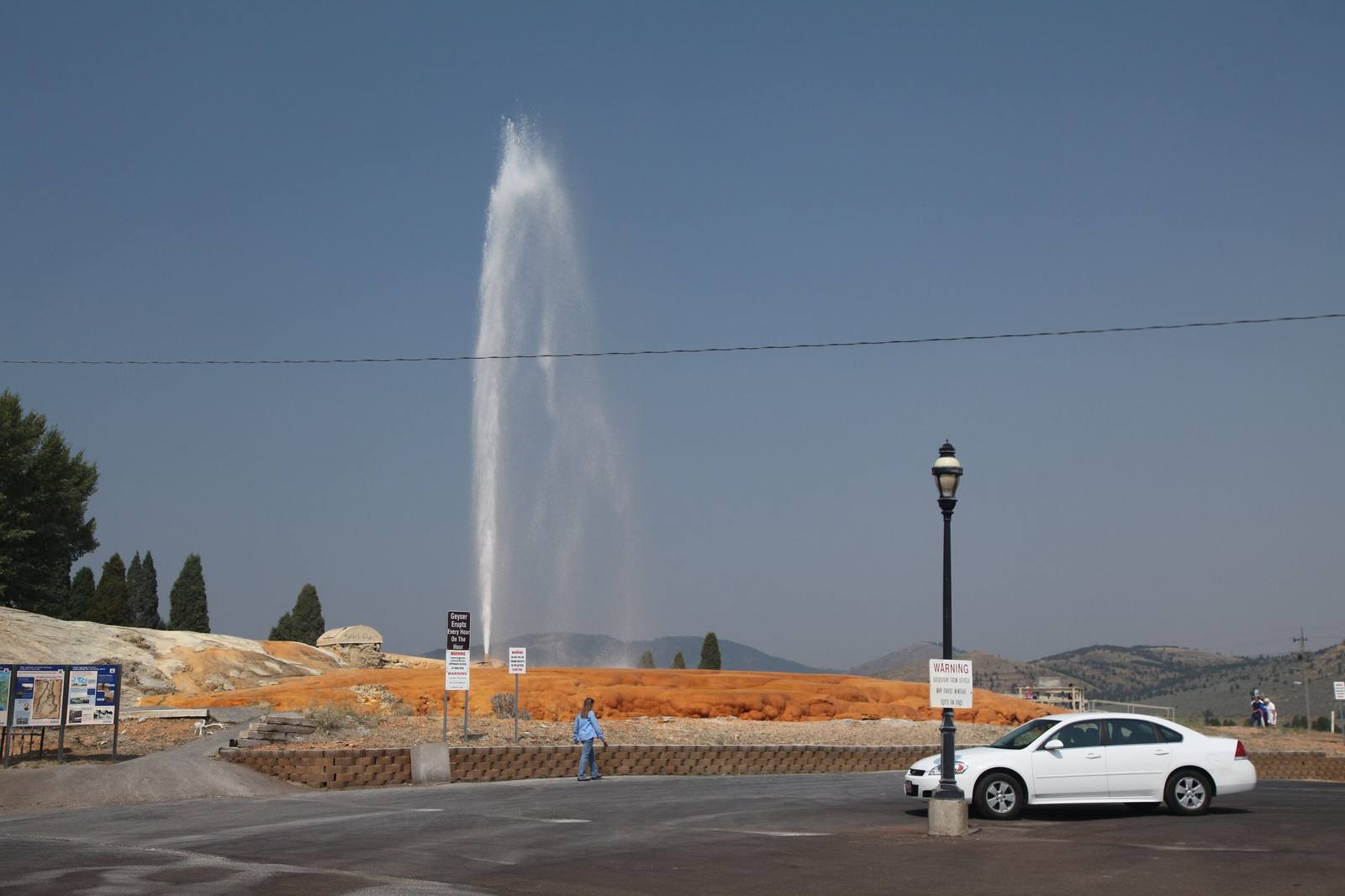 The Soda Springs geyser erupting above its orange mineral terrace beside a town street