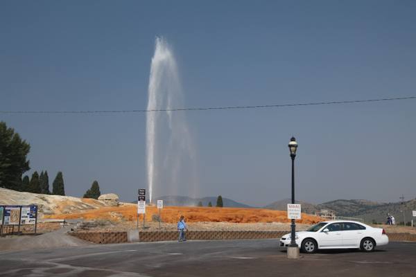 The Soda Springs geyser erupting above its orange mineral terrace beside a town street