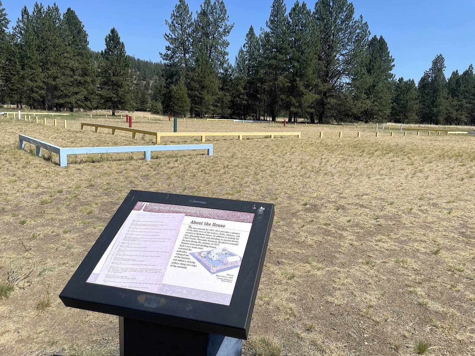 The site of Spokane House in Riverside State Park, the trading post's footprint traced with low timber outlines in the grass beside an interpretive sign