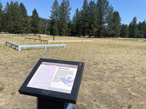 The site of Spokane House in Riverside State Park, the trading post's footprint traced with low timber outlines in the grass beside an interpretive sign