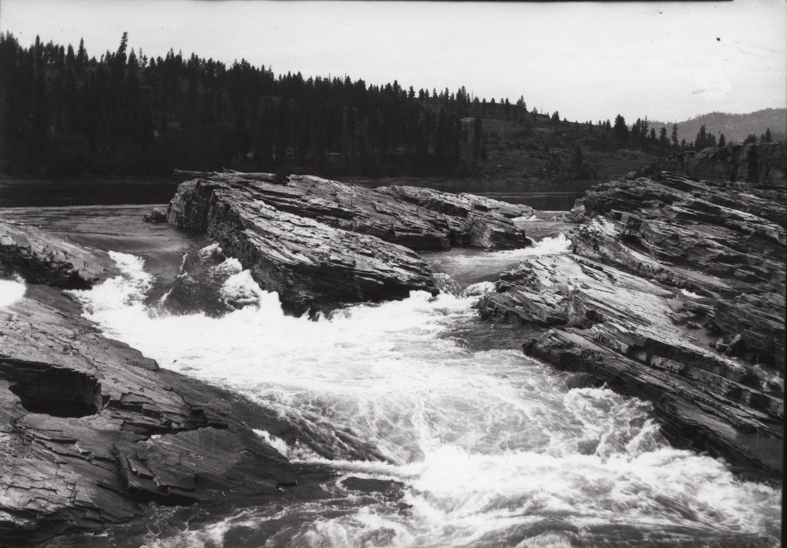 The Lower Kettle Falls of the Columbia around 1930, white water pouring between tilted rock ledges, a decade before Lake Roosevelt covered them