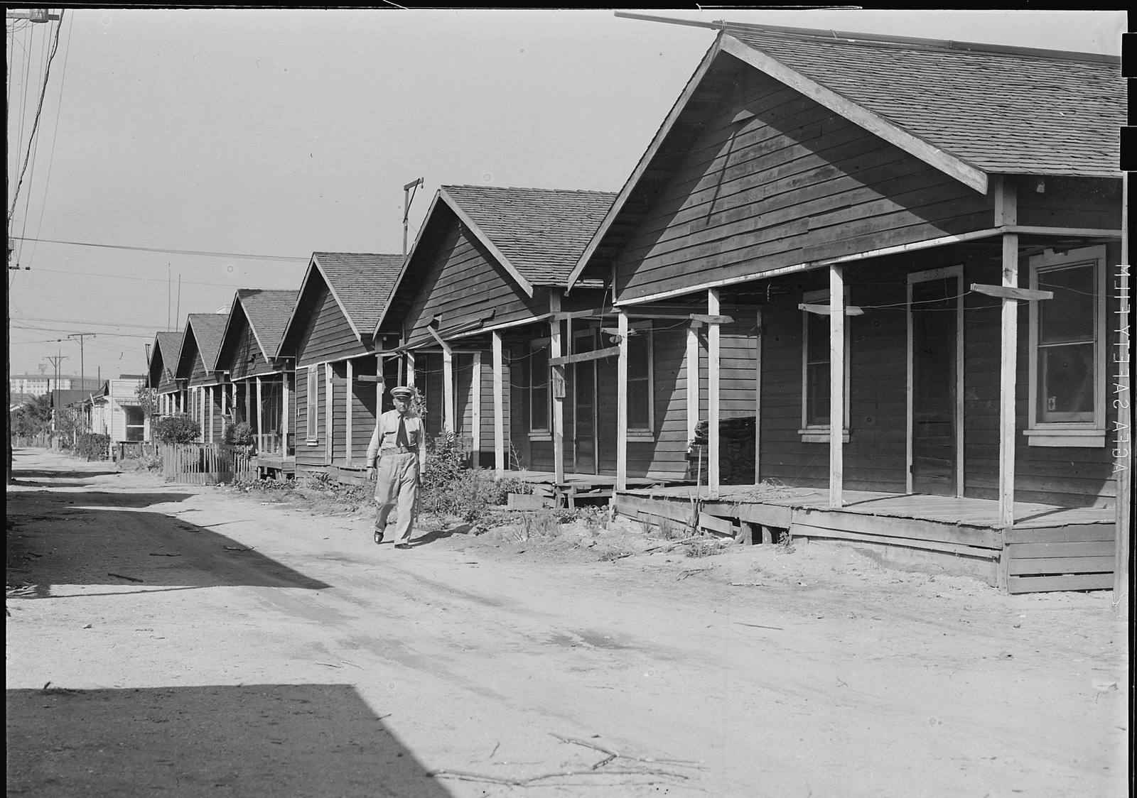A row of wooden cottages along a dirt street at Terminal Island in 1942, photographed after its Japanese American residents were removed and before the village was demolished.