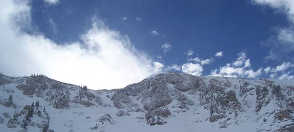 Snow-clad chutes and cliffs above Alta in Little Cottonwood Canyon, Utah, under a blue winter sky.