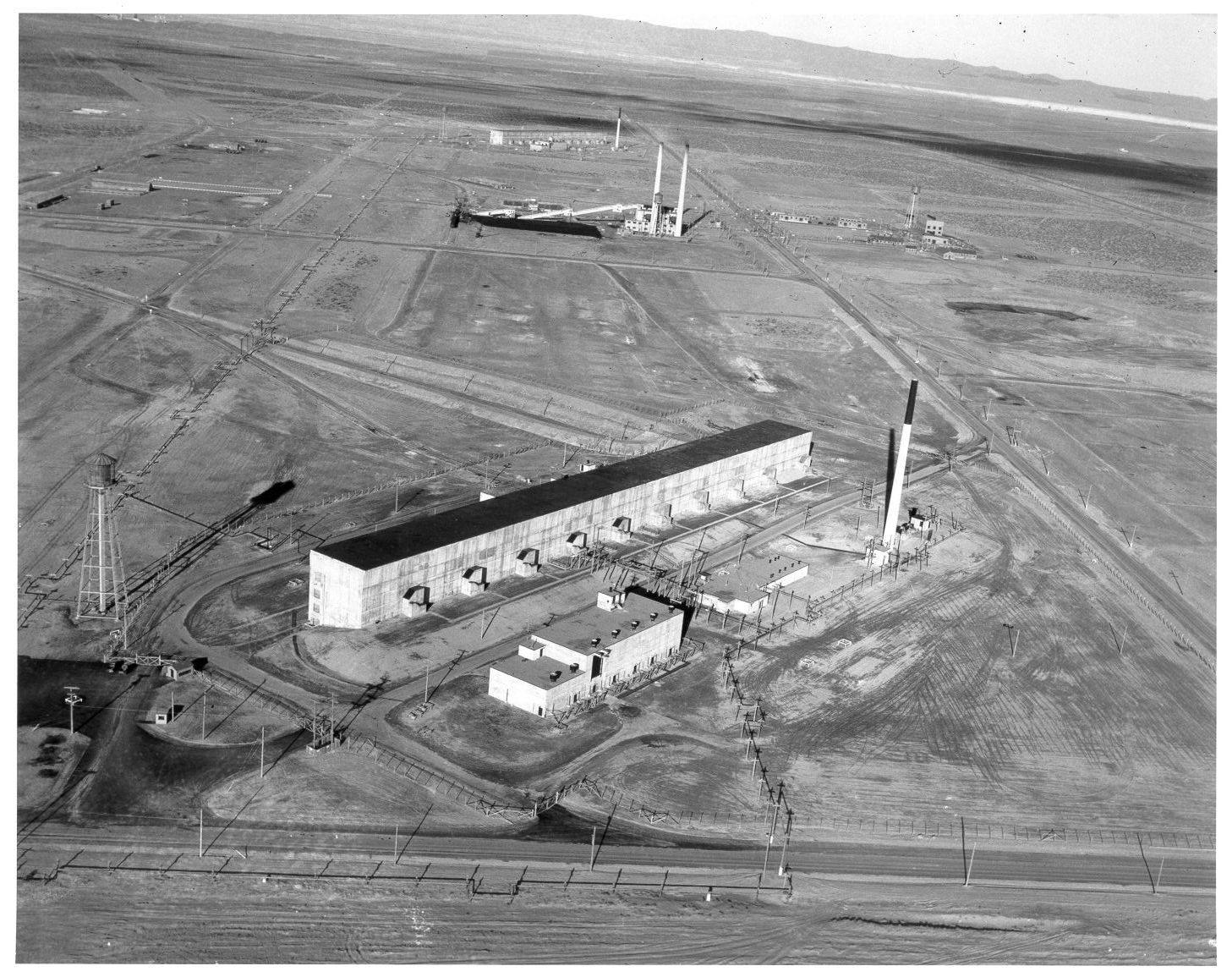 Hanford's T Plant in December 1944, the long concrete separations building and its tall stack standing on bare, graded desert in the 200 West Area