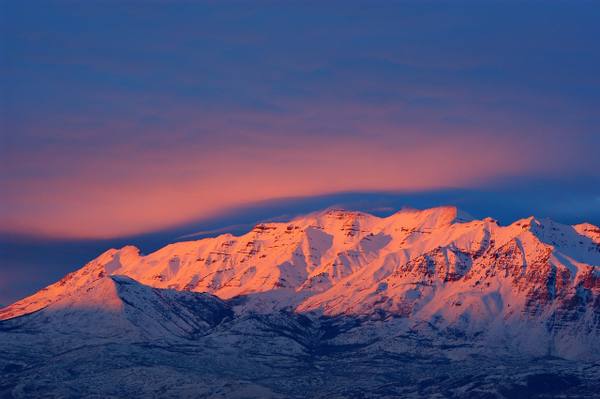 Mount Timpanogos at sunset, its long snow-capped ridgeline catching alpenglow above Utah Valley — the reclining profile behind the 'sleeping princess' legend.
