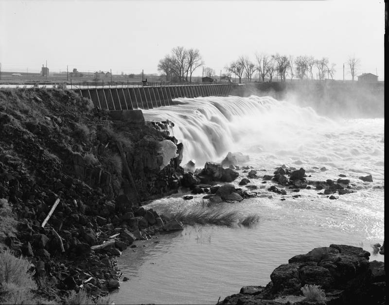 Water spilling over the gates of Milner Dam onto basalt, in a Historic American Engineering Record photograph