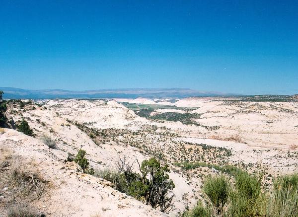 Green ranchland in a valley amid the white slickrock and canyon country of the Hogsback on Scenic Byway 12, the remote road into Boulder, Utah.
