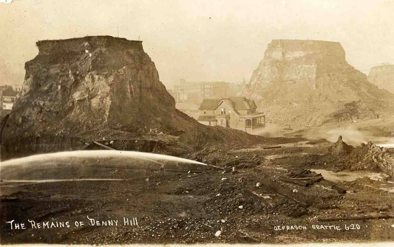 A 1920 postcard captioned The Remains of Denny Hill: two flat-topped towers of earth left standing, a house on one, while a hydraulic jet washes the ground away below