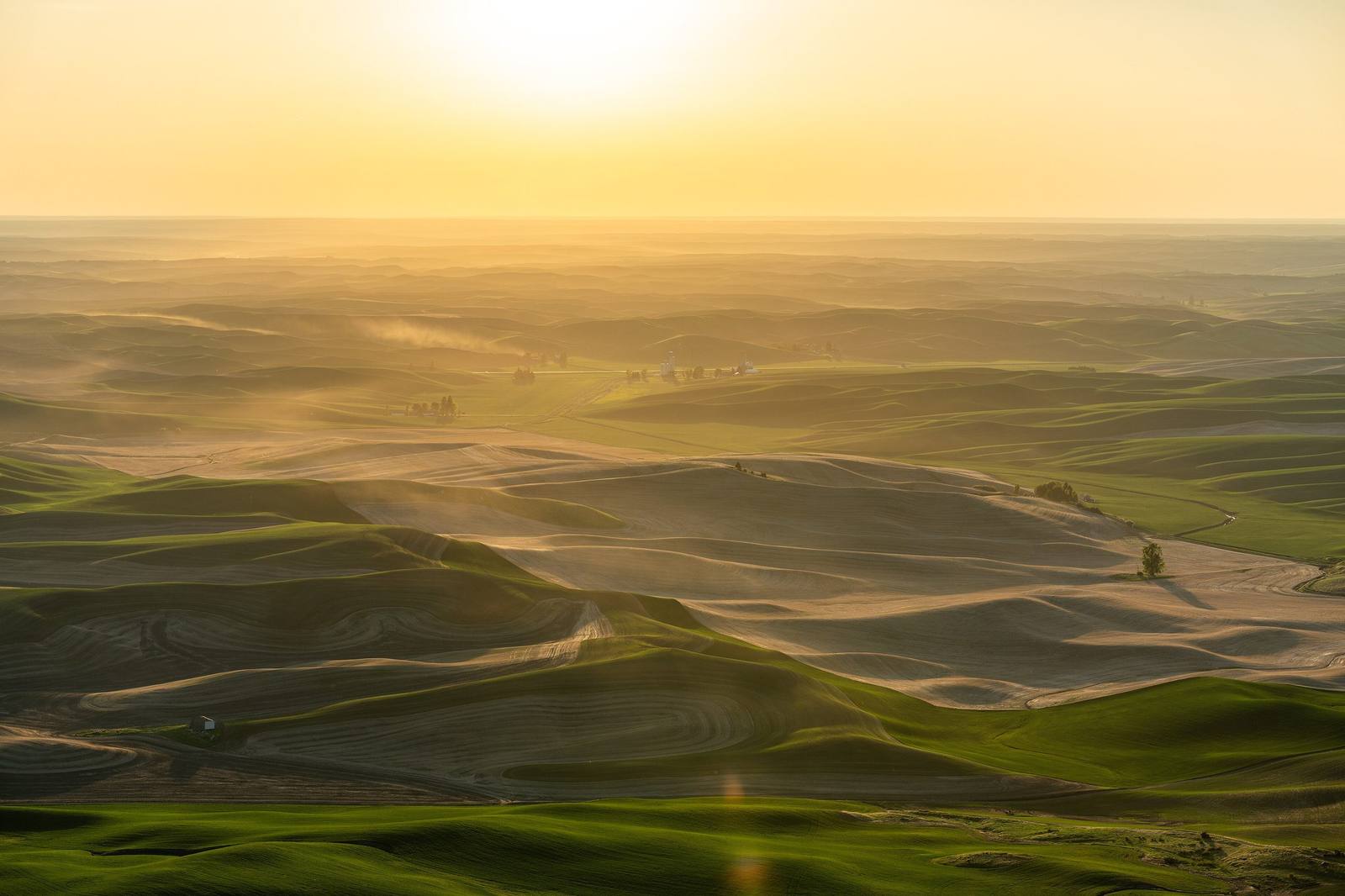 The rolling hills of the Palouse fading into a hazy golden sunset, seen west from Steptoe Butte