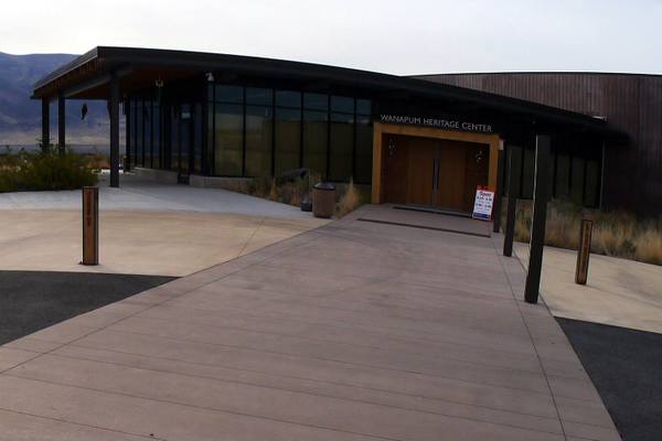 The entrance of the Wanapum Heritage Center, a long glass-and-timber building with its name over the doors and dry hills behind