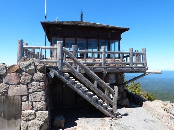 The 1932 Watchman fire lookout on its stone base, log stairs climbing to the glassed cab on the summit