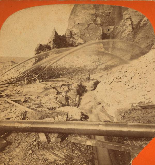 A hydraulic mining monitor driving a jet of water against a hillside at the Palm claim, Timbuctoo, Yuba County, photographed between 1866 and 1874.