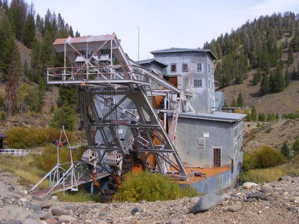 The steel-clad Yankee Fork gold dredge and its bucket ladder sitting on its tailings among pines